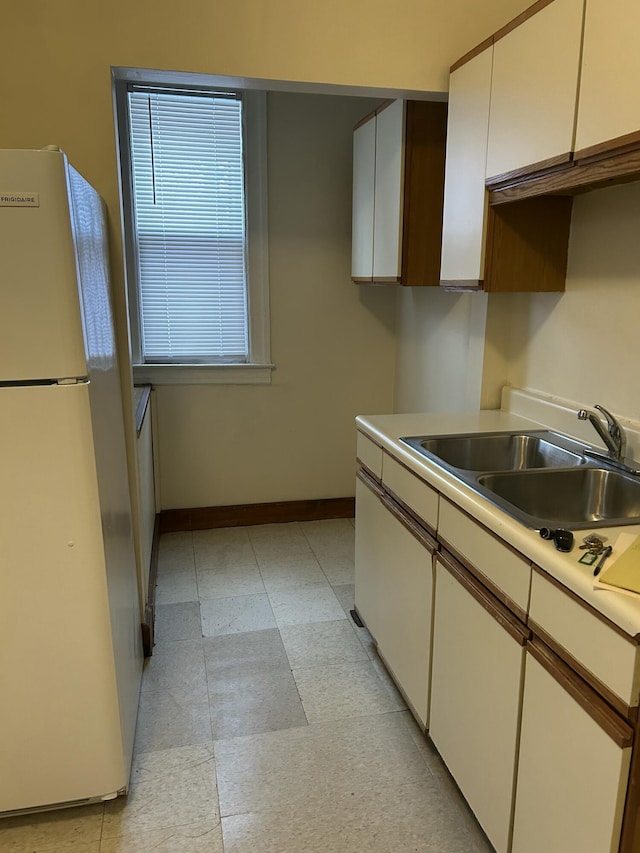 kitchen with white cabinets, refrigerator, and sink