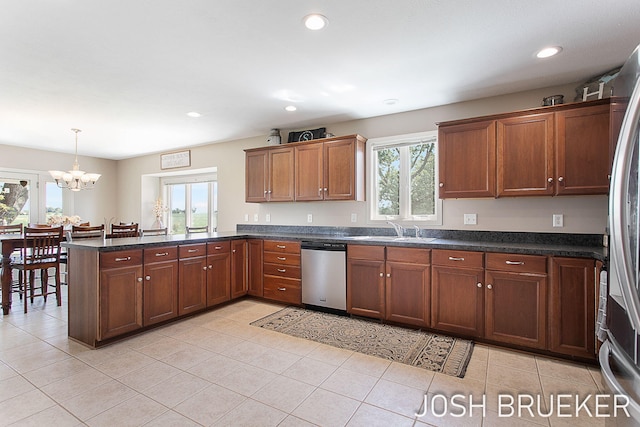 kitchen with pendant lighting, sink, kitchen peninsula, stainless steel appliances, and an inviting chandelier