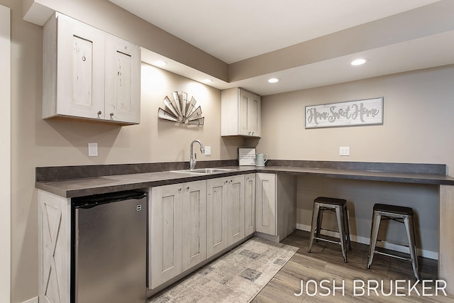 kitchen with wood-type flooring, sink, and stainless steel refrigerator