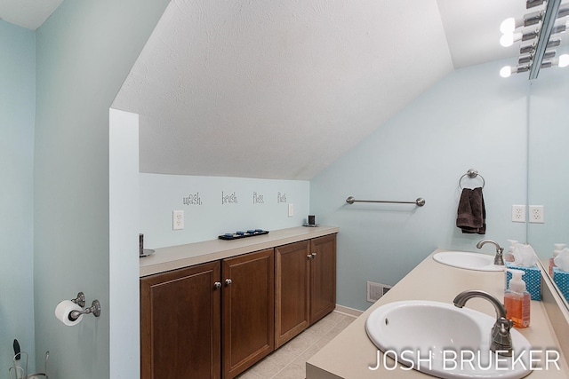 bathroom featuring tile patterned flooring, vanity, lofted ceiling, and a textured ceiling