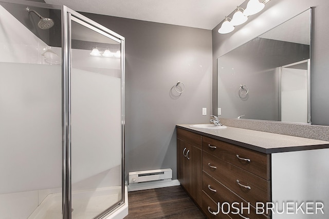 bathroom with vanity, an enclosed shower, wood-type flooring, and a baseboard heating unit