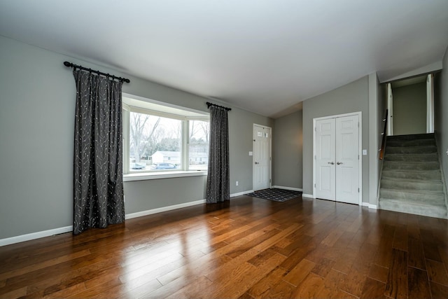 empty room with dark wood-type flooring and lofted ceiling