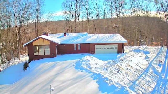 view of front of home with a garage, a forest view, metal roof, and a standing seam roof