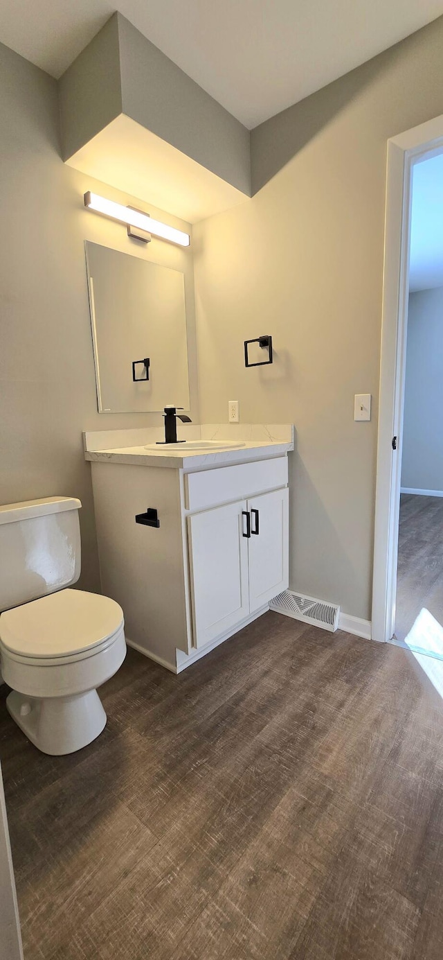 bathroom featuring vanity, wood finished floors, toilet, and baseboards