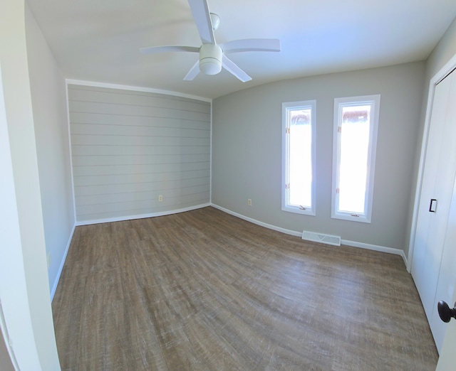 empty room featuring baseboards, ceiling fan, visible vents, and wood finished floors