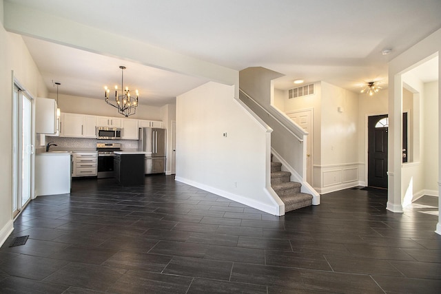 kitchen featuring an inviting chandelier, decorative light fixtures, stainless steel appliances, decorative backsplash, and white cabinets