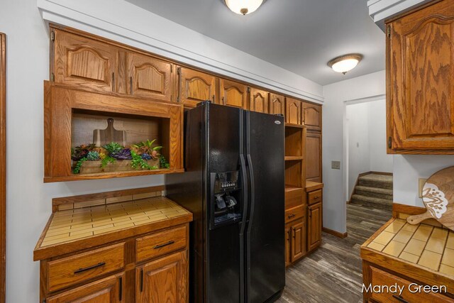 366 E Beech St NE, Cedar Springs, MI 49319 - kitchen with black fridge with ice dispenser, tile counters, open shelves, dark wood-style flooring, and brown cabinetry