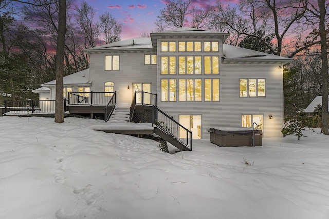 snow covered property with a deck and a hot tub