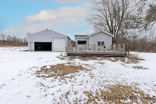 snow covered property with an outbuilding, a garage, and a deck