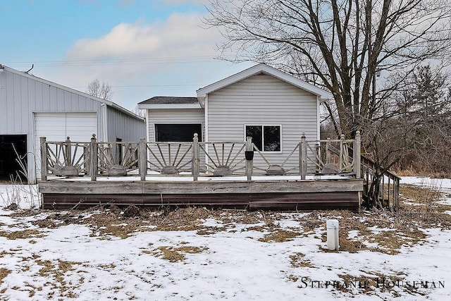 snow covered rear of property with a deck