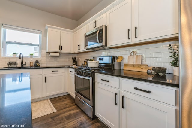 6058 Racine Dr, Stevensville, MI 49127 - kitchen with stainless steel appliances, white cabinetry, decorative backsplash, dark wood finished floors, and a sink