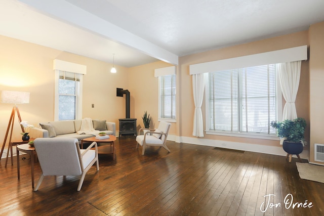 living room with dark hardwood / wood-style floors, beam ceiling, and a wood stove