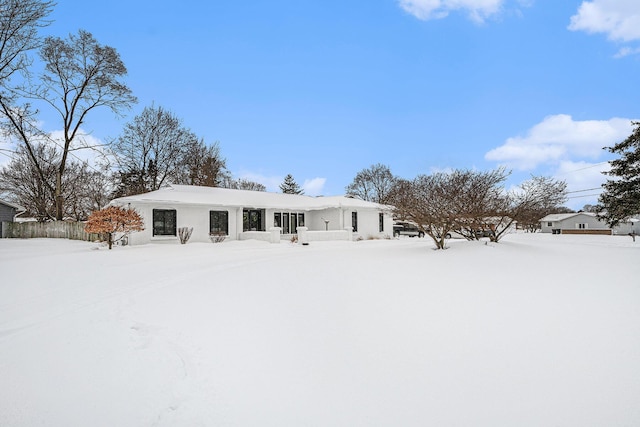 snow covered back of property featuring stucco siding