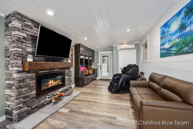 living room featuring a wall unit AC, recessed lighting, light wood-style flooring, a stone fireplace, and wooden ceiling