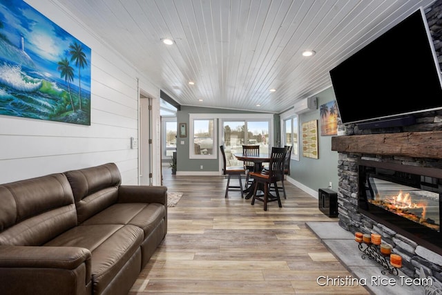 living area featuring light wood finished floors, wood ceiling, vaulted ceiling, a stone fireplace, and recessed lighting