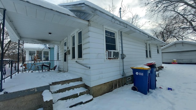 snow covered property with cooling unit, a garage, and an outdoor structure