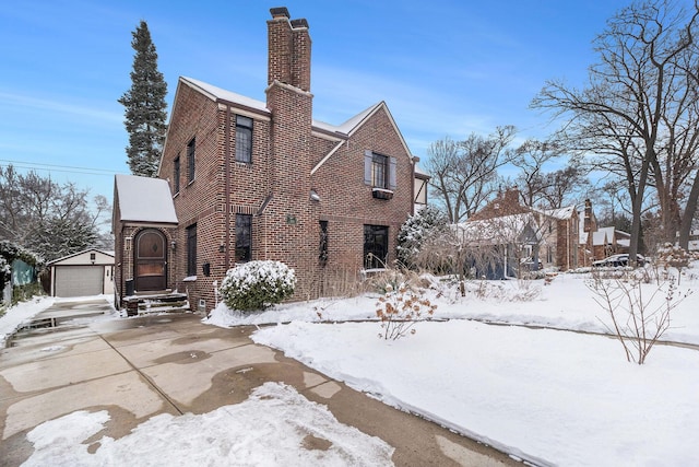 snow covered property featuring a garage and an outdoor structure