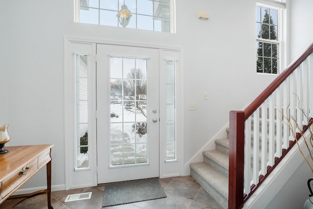 entryway with tile patterned floors, visible vents, and stairway