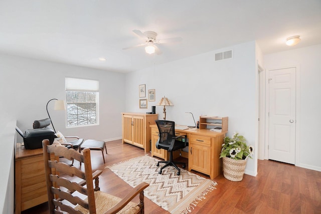 office space featuring visible vents, baseboards, ceiling fan, and wood finished floors