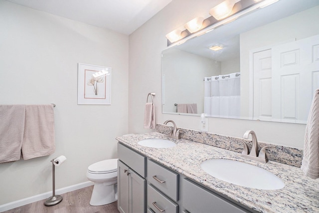 full bath featuring toilet, wood finished floors, baseboards, and a sink