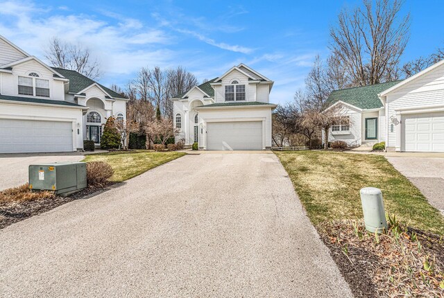 traditional home featuring a front lawn, an attached garage, and driveway
