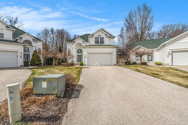 traditional home featuring a garage, driveway, and a front lawn