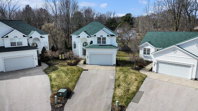 traditional-style home featuring a shingled roof, a garage, and a front yard