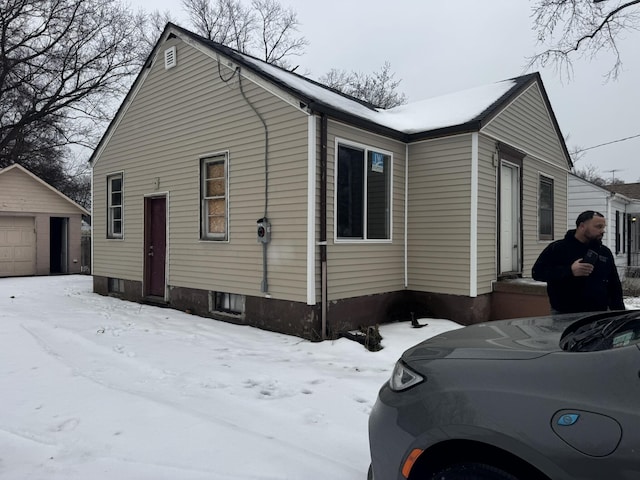 view of snowy exterior with a garage and an outbuilding