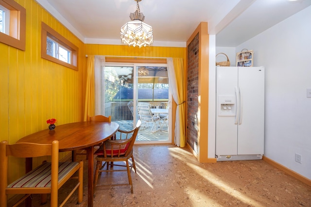 dining area with an inviting chandelier and wooden walls