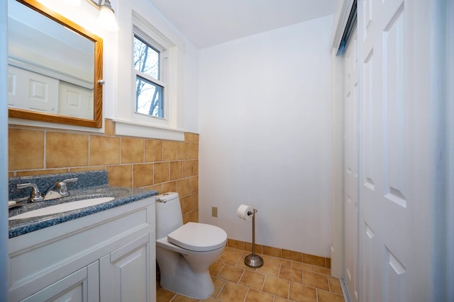 bathroom featuring tile patterned floors, vanity, toilet, and tile walls