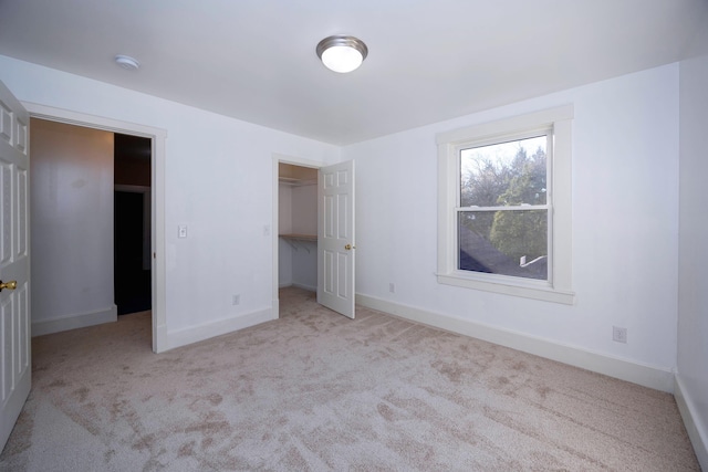 unfurnished bedroom featuring light carpet, a spacious closet, and a closet