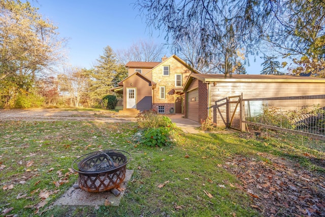 view of front facade with a garage, a front yard, and a fire pit