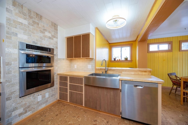 kitchen with appliances with stainless steel finishes, sink, kitchen peninsula, and butcher block countertops