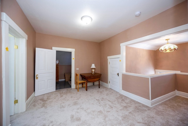 unfurnished room with light colored carpet and a notable chandelier