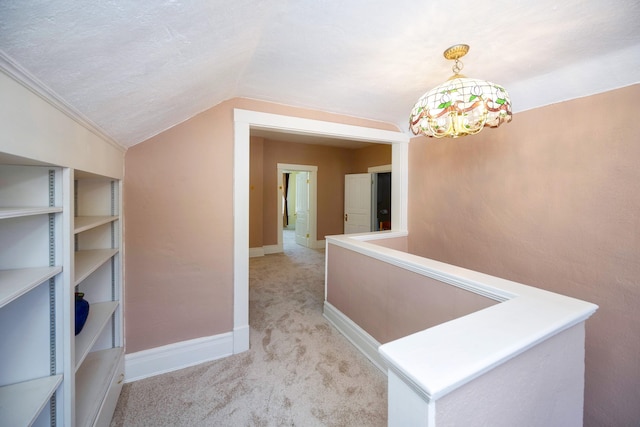 corridor featuring lofted ceiling, light colored carpet, a textured ceiling, and an inviting chandelier