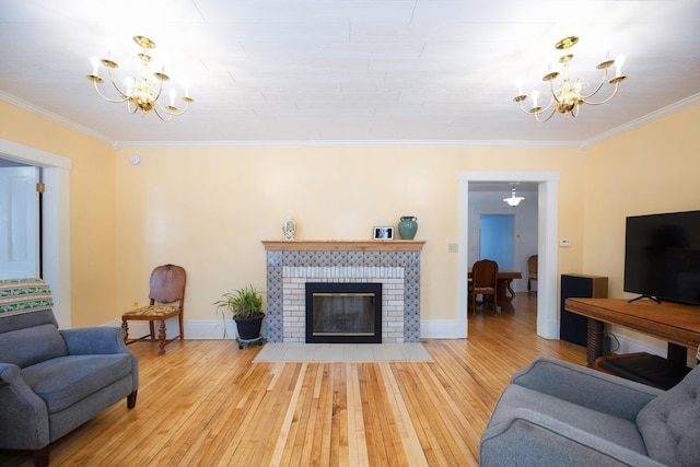 living room with a notable chandelier, ornamental molding, light hardwood / wood-style floors, and a brick fireplace