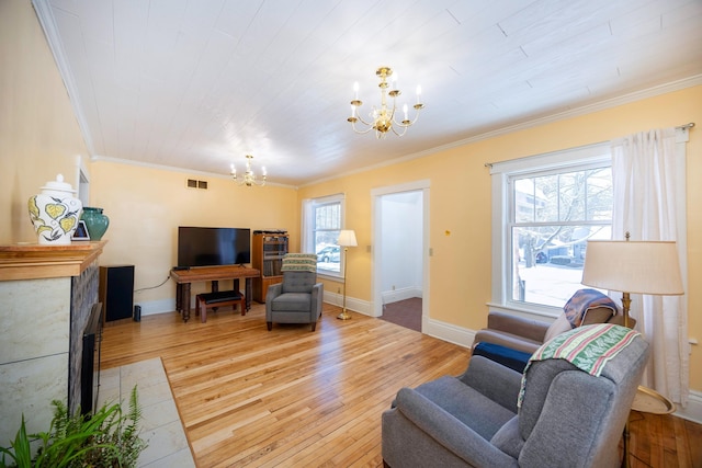 living room with ornamental molding, plenty of natural light, a chandelier, and light hardwood / wood-style flooring