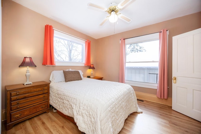 bedroom featuring ceiling fan, light hardwood / wood-style floors, and multiple windows