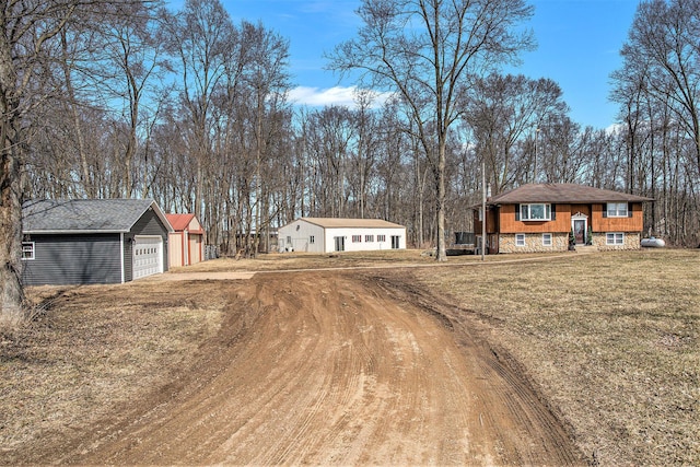 exterior space featuring a front yard, an outdoor structure, a garage, and dirt driveway