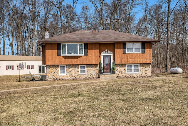 split foyer home featuring stone siding and a front yard