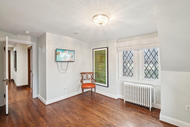 unfurnished room featuring baseboards, radiator, and wood finished floors