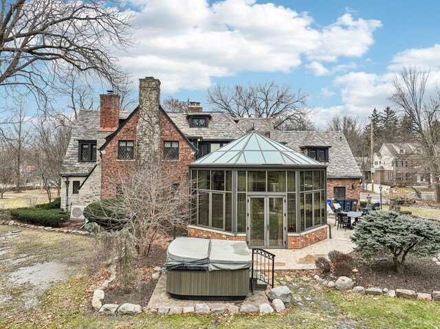 rear view of property with a patio area, a chimney, a sunroom, and a hot tub
