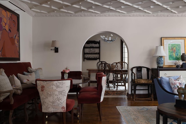 dining area with arched walkways, a chandelier, and wood finished floors