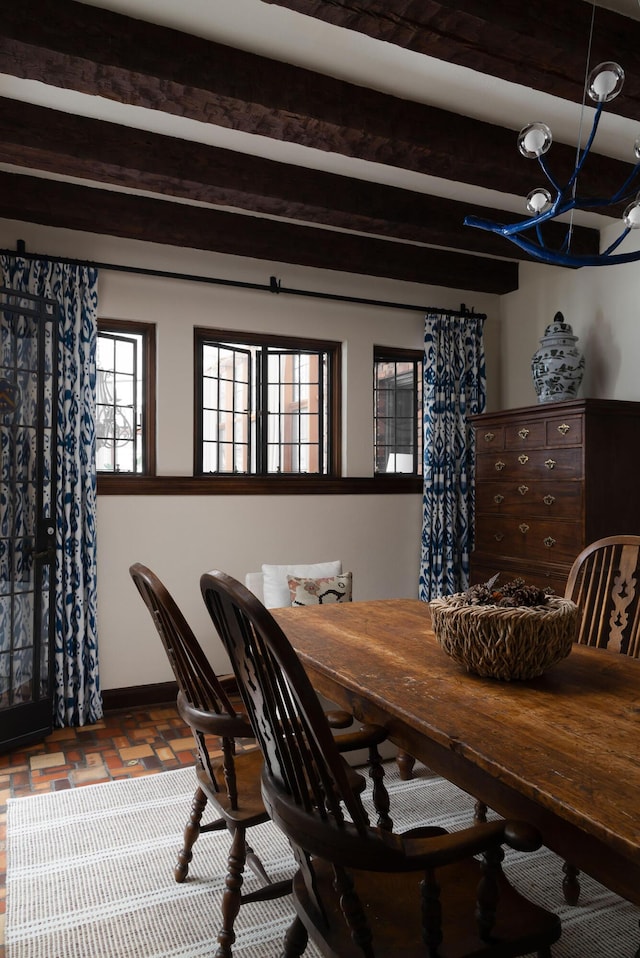 dining room with beamed ceiling, baseboards, and an inviting chandelier