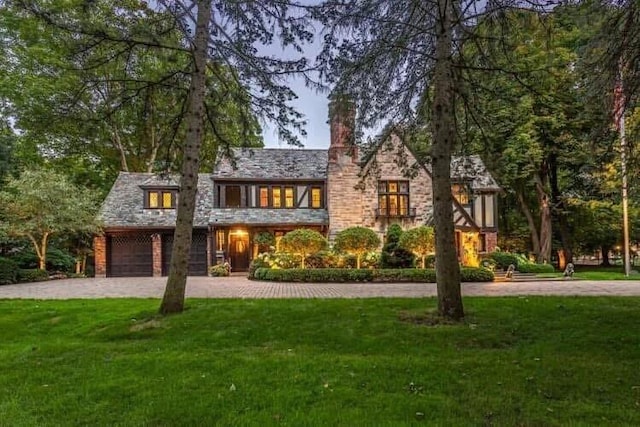 view of front of house featuring a front yard, curved driveway, and a chimney