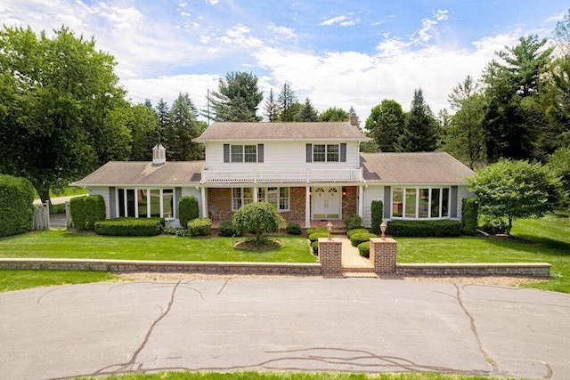 traditional home featuring a front yard, brick siding, and a chimney