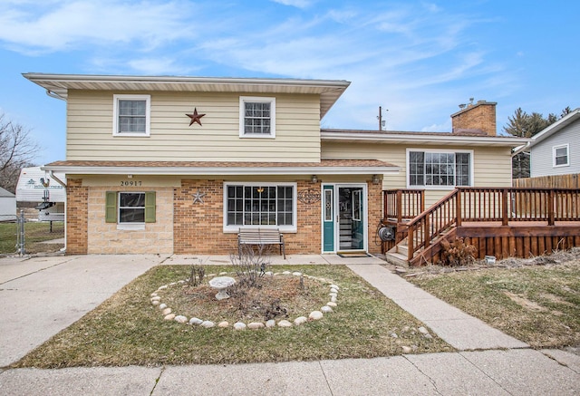 tri-level home featuring brick siding, a chimney, and fence