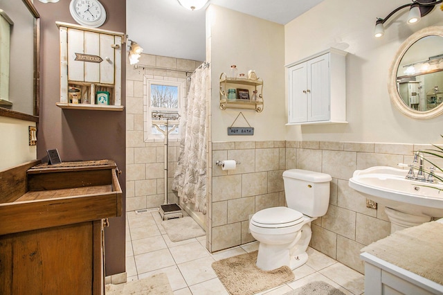 full bathroom with toilet, a shower with curtain, a wainscoted wall, tile patterned flooring, and tile walls