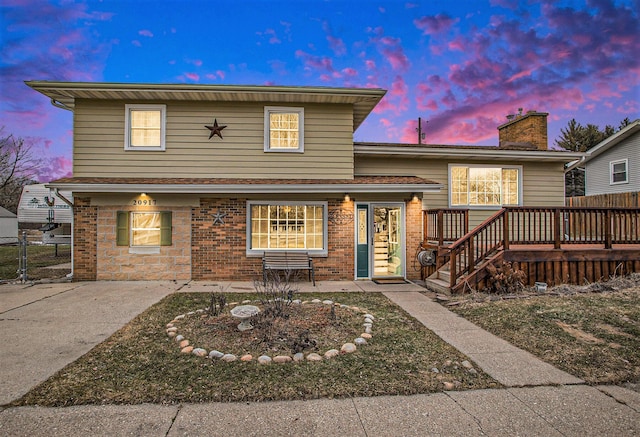 split level home featuring a patio area, fence, and brick siding