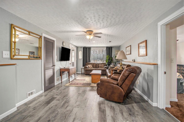 living room featuring baseboards, visible vents, ceiling fan, wood finished floors, and a textured ceiling